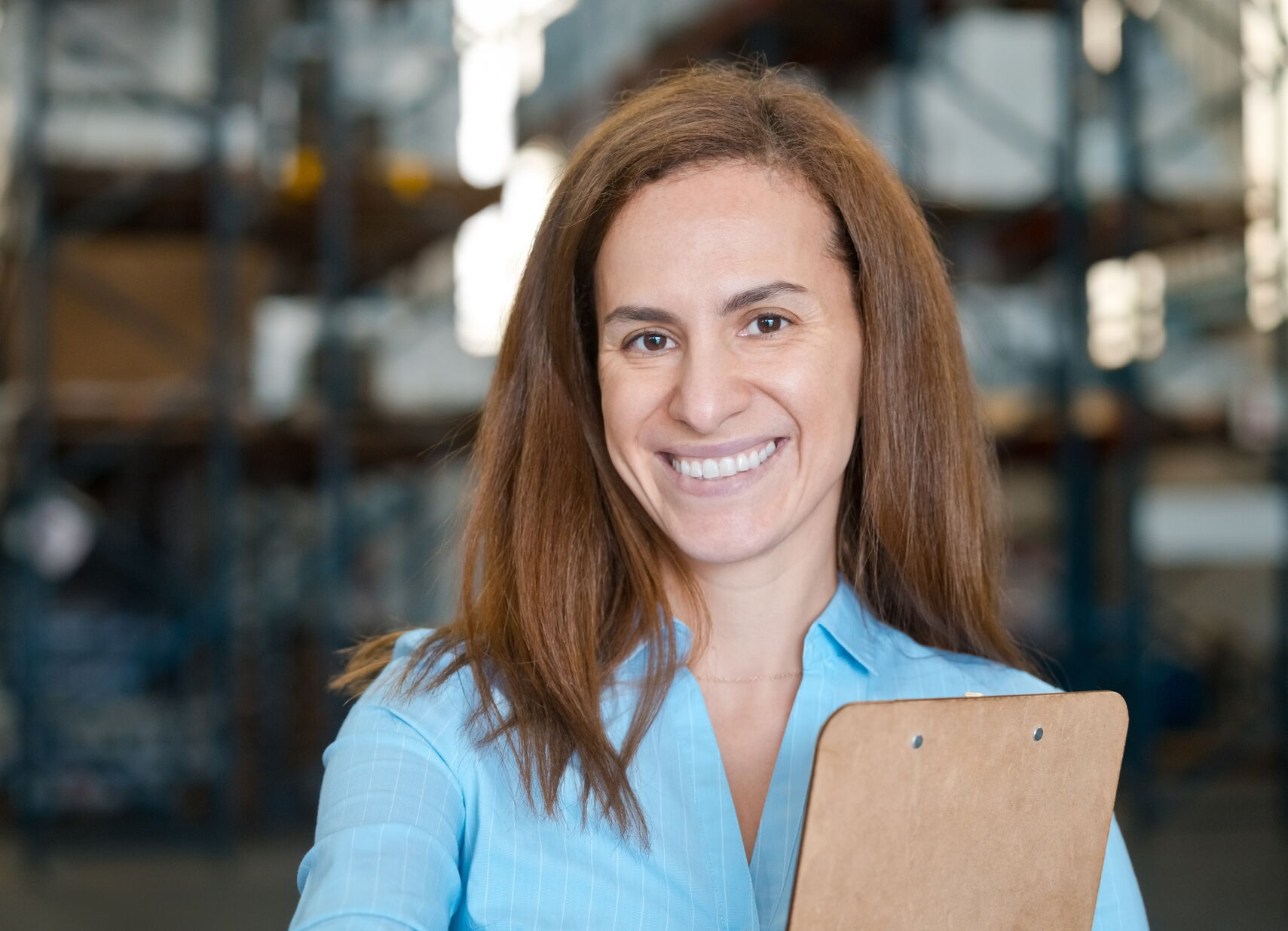 A woman holding a clipboard and smiling